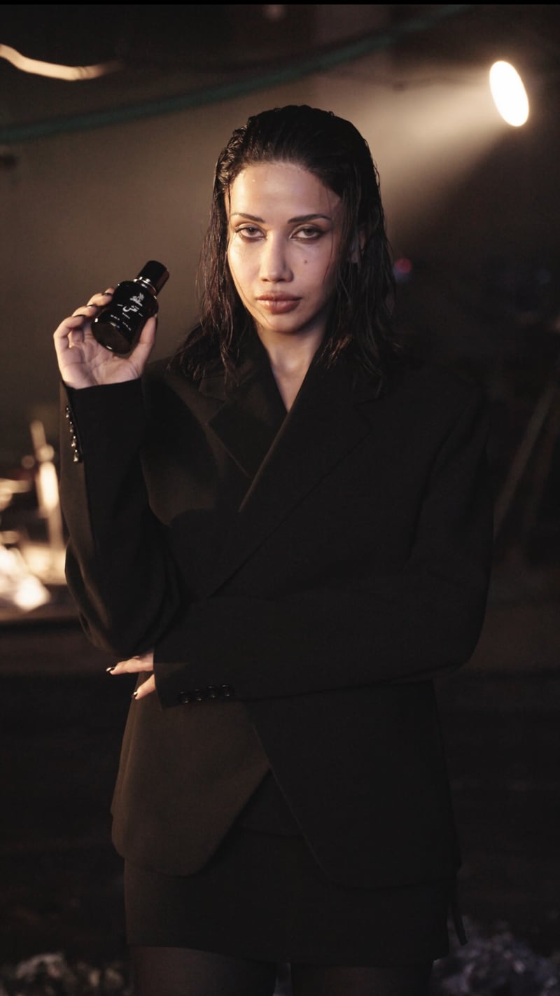 A woman holding the Naqsh flacon beside her face, a still from the film