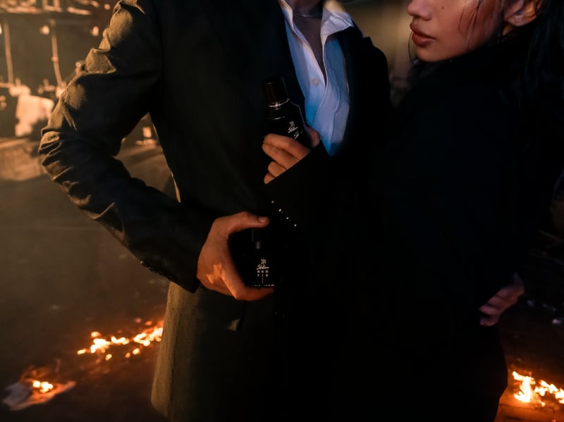 A couple at the fire, the Allure Ice flacon raised between them