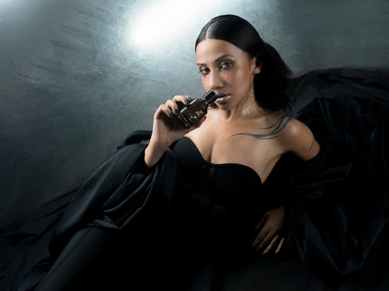 A woman reclining in black against a silver backdrop, the Mehfil flacon in her hand