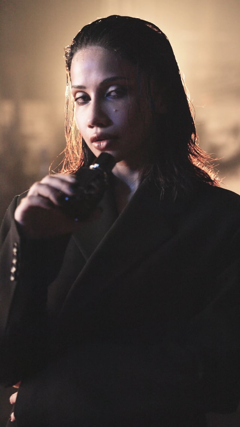 A woman bringing the Naqsh flacon to her mouth, warm light behind her