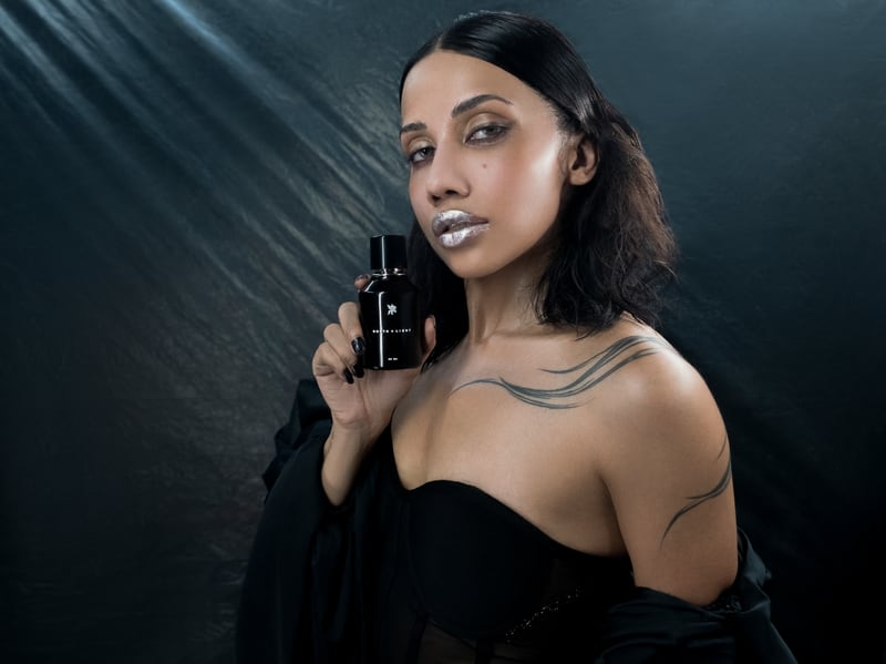 A woman in black holding the North + Light flacon at her collarbone