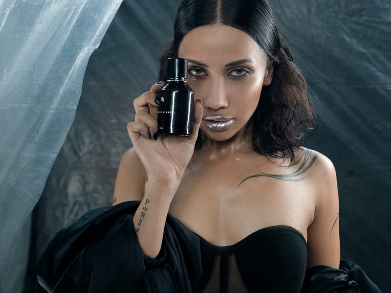 A woman holding the North + Light flacon to her face against a silver backdrop, the label sharp