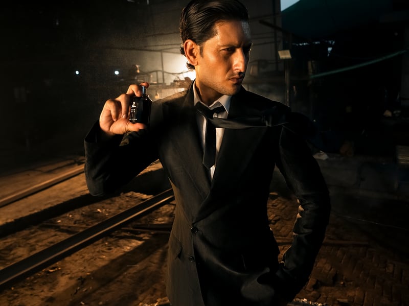 A man in a dark suit spraying the Red Tie flacon at his throat