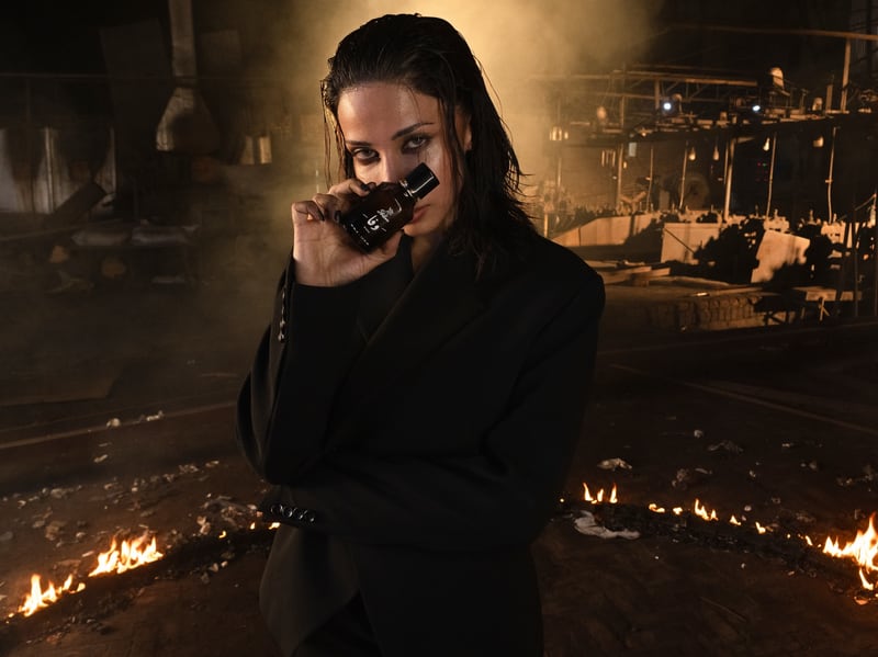 A woman lowering the Wafa flacon, firelight across her face